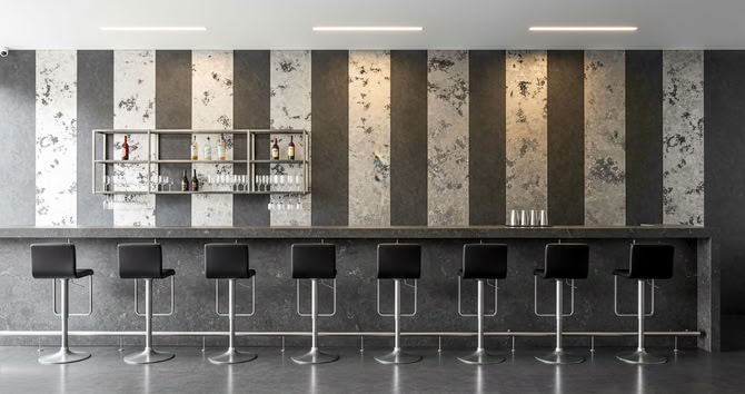 Eine moderne Bar mit neun schwarzen Barhockern vor einer Wand mit vertikalen Streifen mit glaMUR Effektspachtel