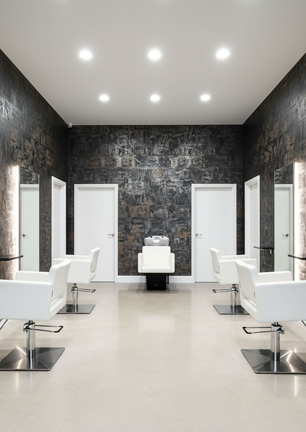 Ein moderner Friseursalon mit weißen Stühlen, großen Spiegeln an den Wänden Effektspachtel Smoke und Rost in Facetten