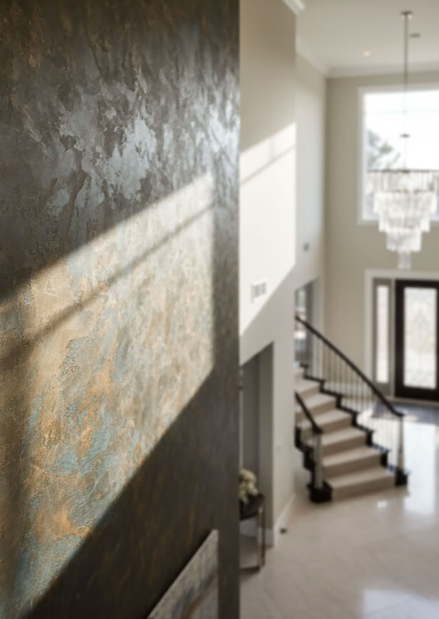 Großer, heller Eingangsbereich eines Hauses mit Treppe, grosse Rostwan, Kronleuchter und Doppeltüren.