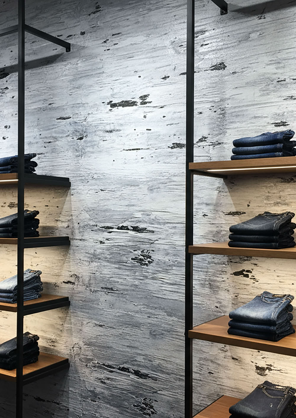 Regale mit gefalteten Jeans vor einer glaMUR Effektspachtel inschwarz und weiss.