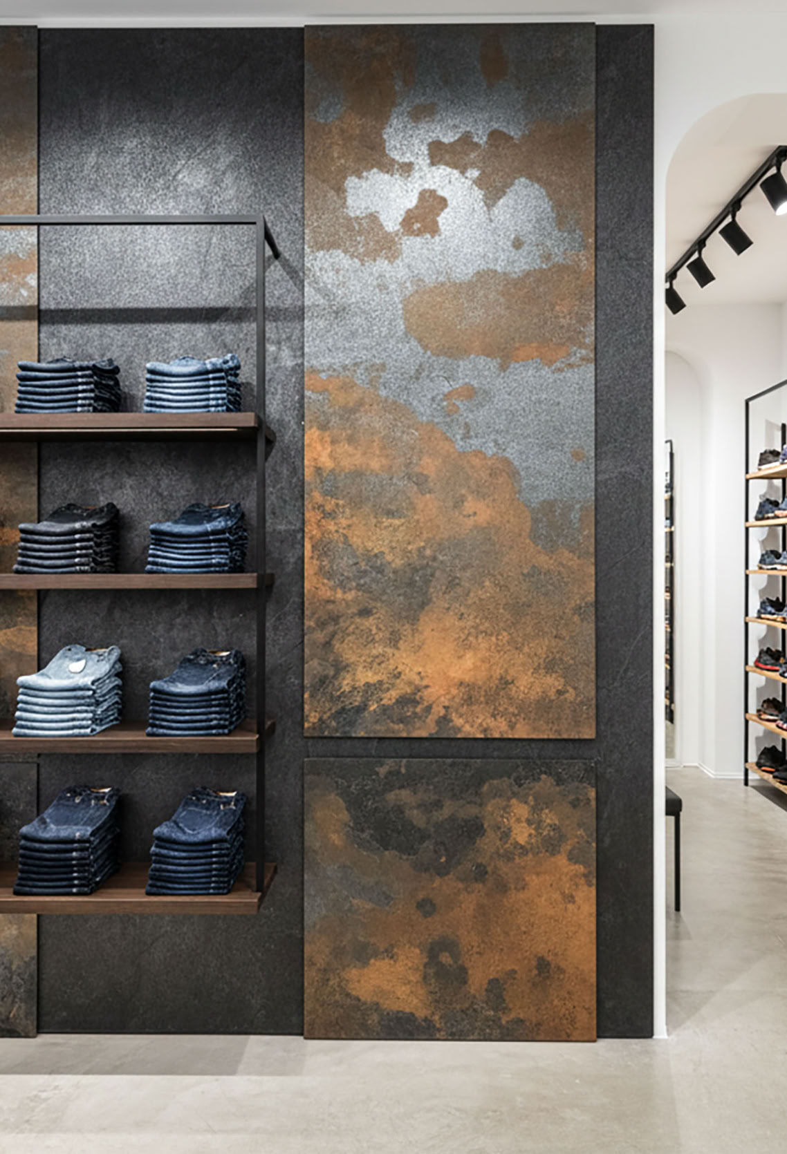 Regal mit gefalteten Jeans vor einer Wand mit Effektspachtel Smoke und Stahl und Spachtelrost.