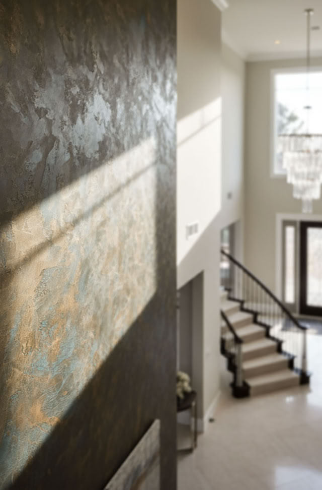 Großer, heller Eingangsbereich eines Hauses mit Treppe, grosse Rostwan, Kronleuchter und Doppeltüren.